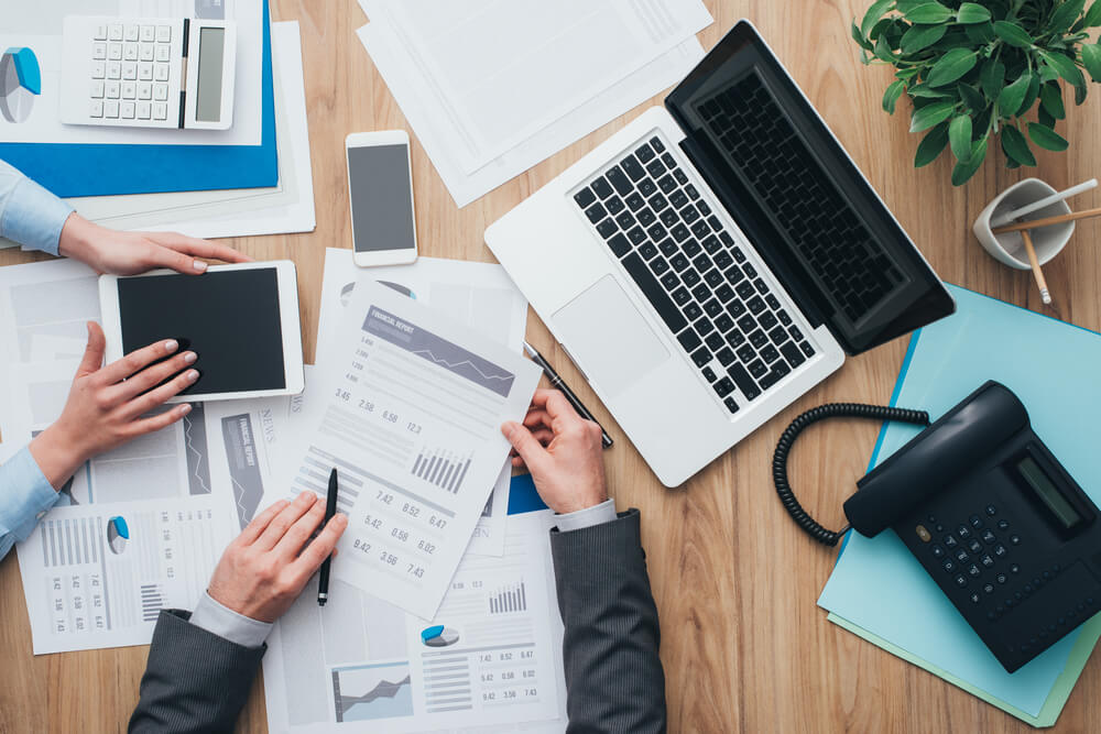 two people looking at business papers and laptop