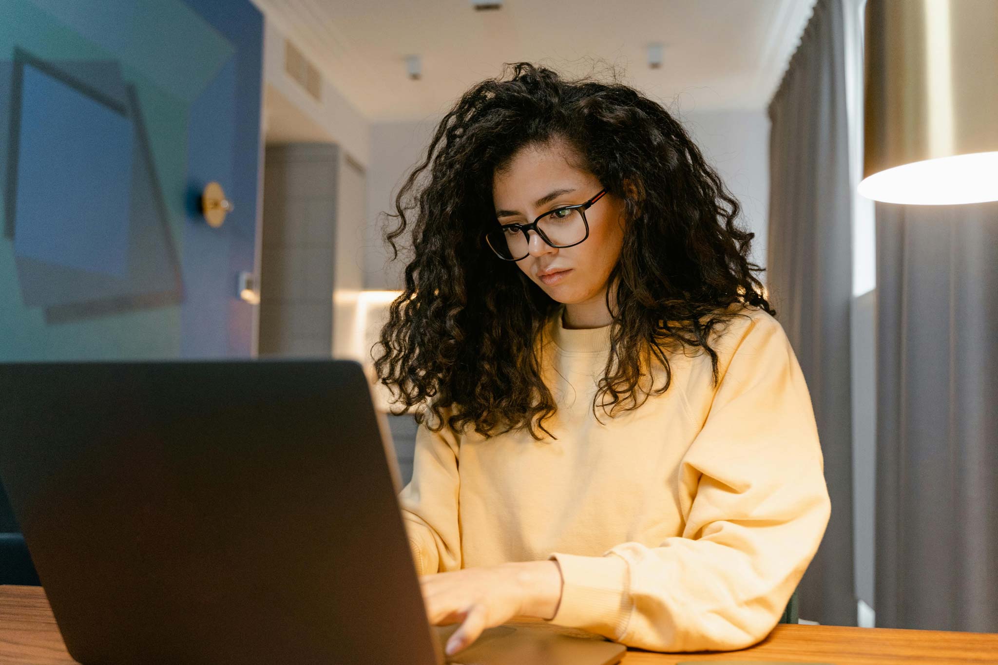 Woman with curly hair typing on laptop
